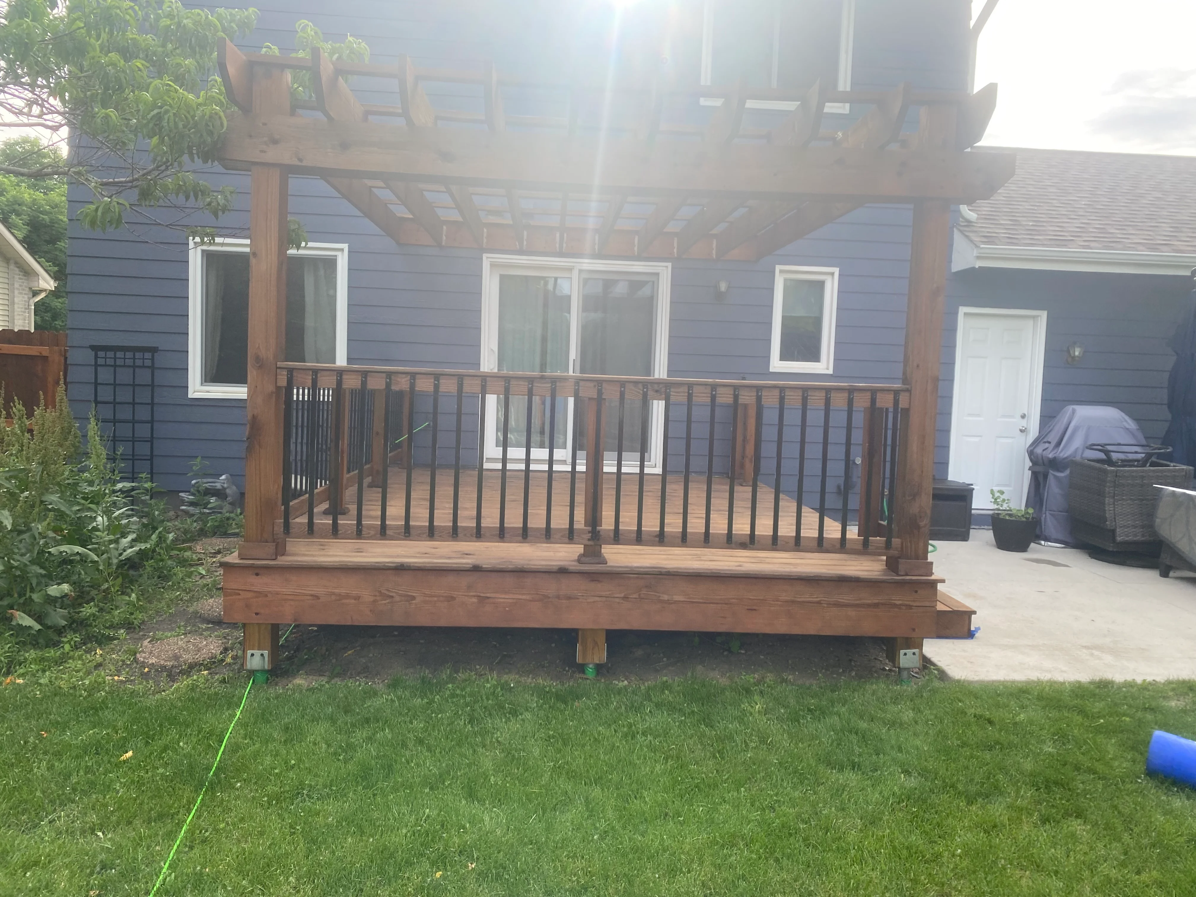 Finished cedar deck and pergola attached to a blue house