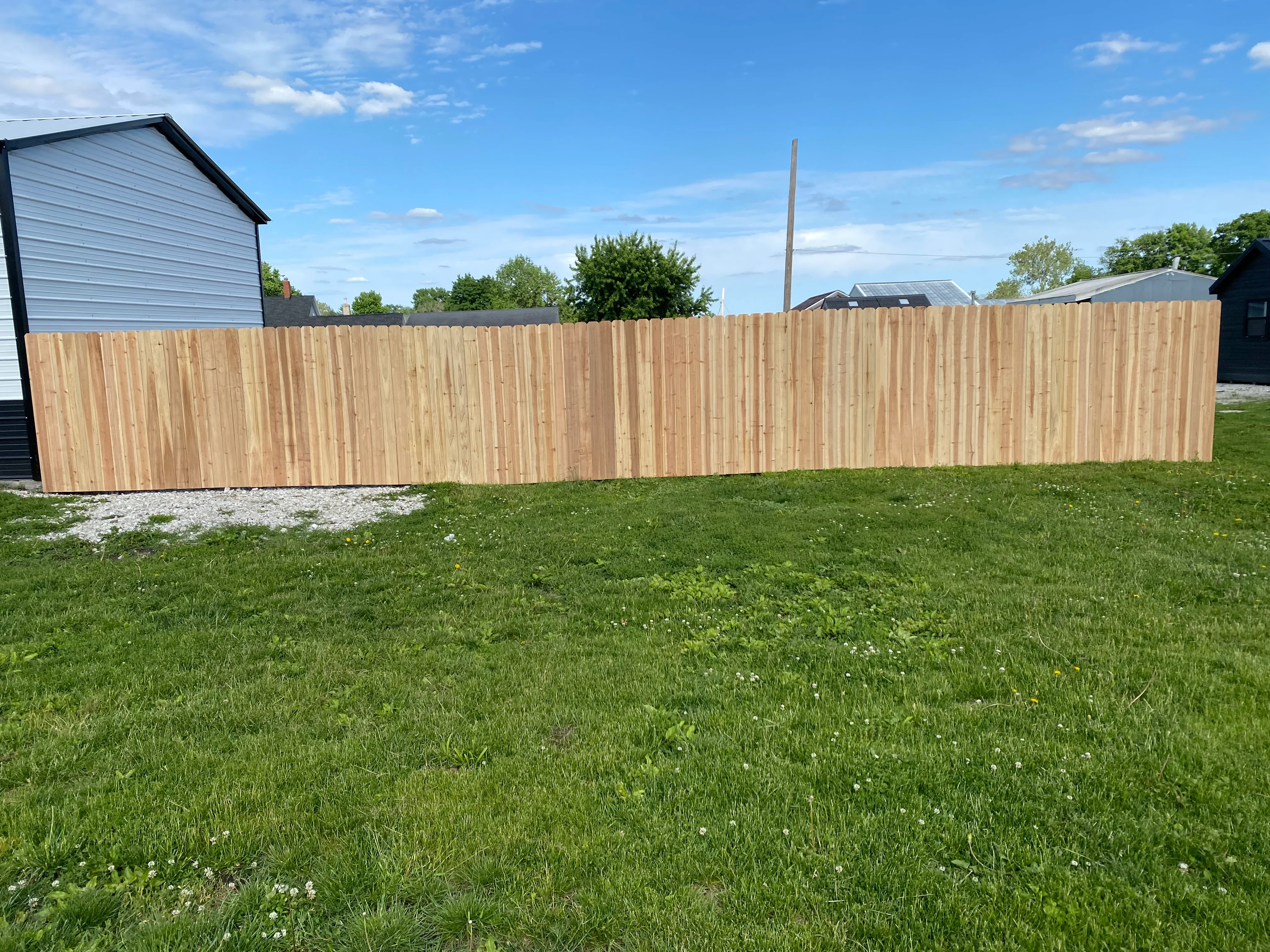 Long finished wood privacy fence across a grassy yard